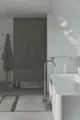 Minimalistischer Badezimmerbereich mit einer platzsparenden Dusche, freistehender Badewanne und einem Handtuchhalter. Produkte von Ideal Standard sind sichtbar.
